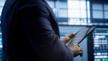 Technician walking in server room, doing checkup, inputting data on tablet of needed fixes. IT professional working in data center facility housing storage infrastructure, camera A photo