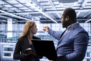 Teamworking colleagues in data center identifying and solving technical issues related to data center infrastructure. IT staff members managing, maintaining and securing server farm environment photo