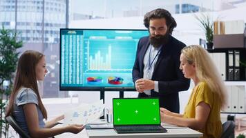 Financial adviser presents market analytics on isolated screen laptop to clients, teaching them how to build portfolio. Broker showing stock exchange charts on chroma key notebook to family, camera B photo