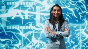 Portrait of smiling IT specialist standing with arms crossed in front of cutting edge display featuring AI and neural network graphics. Researcher in startup doing advancements in AI field, camera A photo