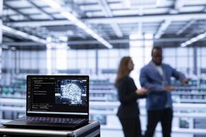 Focus on laptop in data center used by IT experts in blurry background updating AI systems. Close up of notebook used by coworkers using programming to upgrade artificial intelligence simulation model photo