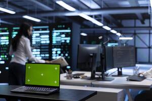 Focus on isolated screen laptop in data center facility managing rackmounts energy consumption. Chroma key notebook used for automation and monitoring processes in server room, close up photo