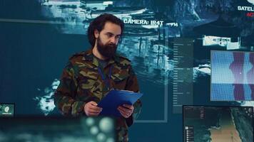 Infantry unit leader coordinating troops to execute special operations, briefing crew with mission details for national safety. Military commander studies real time surveillance data. Camera A. photo