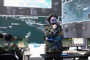 Military staff examining global satellite surveillance footage on a hologram, monitoring troops deployed in the field. Trained army officer employing holographic projection high tech gear. photo