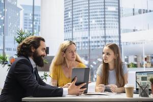 Financial advisor uses software on tablet to calculate clients net worth, taking count of assets and liabilities. Agent in office meeting uses device to help family decide how much money to invest photo