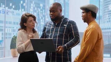 Real estate broker presenting a new high class office space to clients, discussing blueprints using a tablet during the office tour. Planning investment strategy involving property. Camera B. photo