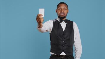 Bellhop personnel offering access card to the room for guests, presenting the key after check in procedure. Hotel porter employee providing lodging and five star amenities at the resort. Camera B. photo