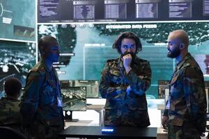 Team of diverse servicemen examining important real time data on a hologram projection, discussing ideas for an ongoing operation. Professional troopers work with holographic image. photo