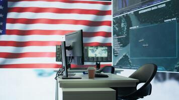 Empty military control center with a big screen shows the American flag, secret service agency protecting the country from threats. Army command room with high tech equipment. Camera B. photo