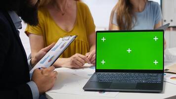 Clients looking over personalized planning guide on green screen laptop written by financial advisor during meeting. Consultant optimizing living expenses for customers using mockup notebook, camera A photo