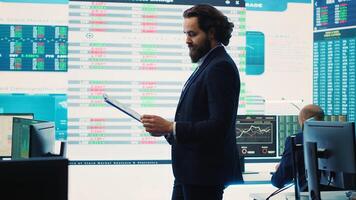 Chief executive officer reviews data shown on big display in the office, screens with infographics, finance analysis and organizational progress. Telecommunications system control room. Camera A. photo