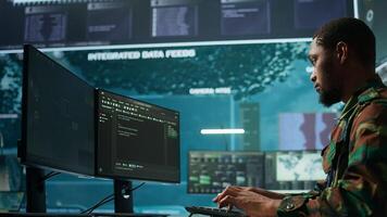 IT expert monitors AI brain intelligence system to collect crucial real time data for a new defense military operation on pc in command post. Security protocols for an intense mission. Camera B. photo