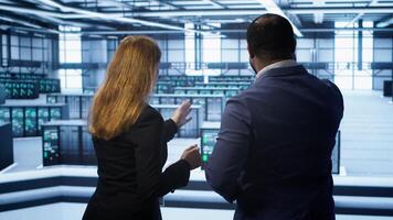 Teamworking admin colleagues inspecting server room hardware. IT expert and colleague supervising data center establishment, checking equipment, monitoring performance, camera A photo