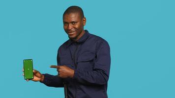 Portrait of happy security guard at work showcasing green screen laptop while overseeing premises. Cheerful private law enforcement worker presenting chroma key notebook, studio backdrop, camera A photo
