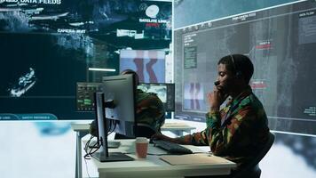 Army professional in uniform works in a mission control center, coordinating surveillance systems and processing intelligence data for operations. Ensuring strategic planning and defense. Camera B. photo