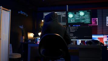 Cybercriminal fraudulently breaching security systems while hiding in secret HQ. Hacker breaking down security systems defenses using rogue scripts to steal valuable data, camera B photo