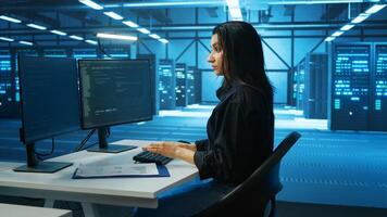 System administrator at PC desk working in computer network security data center, ensuring optimal performance. Employee monitoring energy consumption across operational server rigs components photo