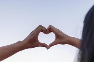 Valentine couples use their hands to make heart symbols to symbolize friendship and loving-kindness towards their lover and friends because heart symbols signify love, friendship and kindness. photo