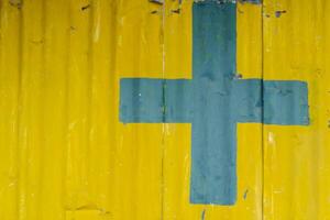 A cross on a yellow metal wall background alerts you to safety when approaching a building area. Cross symbol on a yellow background and Copy Space for entering text. photo
