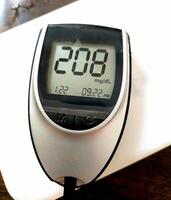 A close up of blood glucose meter with high sugar reading on wooden table photo