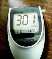 A close up of blood glucose meter with high sugar reading on wooden table photo