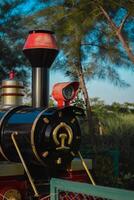 Discover the charm of a bygone era in this vibrant miniature train engine, nestled amidst the verdant splendor of a picturesque park. Timeless wonder and whimsy abound. photo