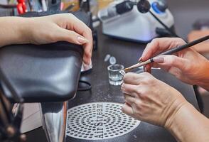 Close-up of a nail technician using a brush to apply gel to a nail in a salon setting photo