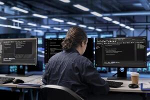 Programmer in server farm establishment ensuring data remains shielded from potential threats. Worker at computer desk safeguarding data center against unauthorized access photo