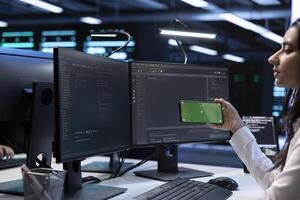 Programmer in data center taking break from work, using isolated screen mobile phone to relax. Worker in server room taking pause from checking systems bottlenecks to use mockup smartphone photo