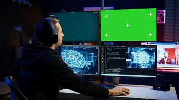 Hacker uses green screen PC and AI deep learning to develop zero day exploit undetectable by antivirus. Scammer uses artificial intelligence and mockup computer to build data mining script, camera B photo