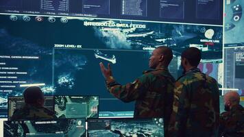 High ranking military personnel briefs the crew for a new federal mission, showing CCTV footage of satellite radar target ships for reconnaissance. Army officers provide intelligence. Camera B. photo