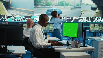 African american employee using greenscreen display and CCTV real time footage, communicating gps coordinates for order shipment and delivery. Control center operator uses surveillance. Camera B. photo