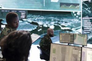 Female trooper checking real time battlefield data in command post control room, examining special missions and operations. Team of recruits interpret satellite imagery for reconnaissance. photo