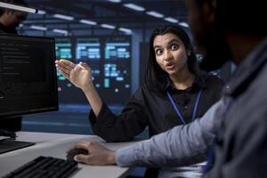 Technician arguing with colleague after seeing error in server hub while overseeing supercomputers. Overworked employee in data center arguing with coworker after noticing malfunction photo