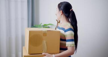 Handheld shot, Happy young woman holds a cardboard box while standing and admiring her new home. Moving house and lifestyle concept. video