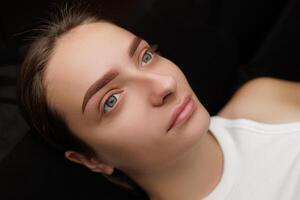 The model has a powder pencil on her eyebrows, which is a sketch before the permanent eyebrow makeup procedure. Permanent eyebrow makeup PMU for brunettes photo