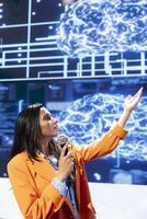 Speaker talking at event bringing together industry experts to share insights on latest advancements in artificial intelligence technology. Woman speaking at conference in front of entrepreneurs photo