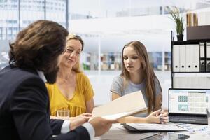 Financial advisor showing clients stock market trends and economic indicators on laptop. Broker using notebook to offer family tailored strategies to help them identify investment opportunities photo