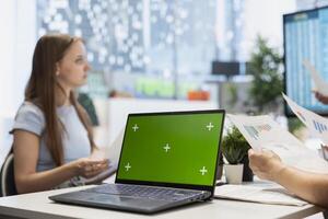 Portfolio Manager analyzing economic reports on isolated screen laptop, discussing with clients. Financial advisor uses chroma key notebook to help customers looking to grow their wealth photo