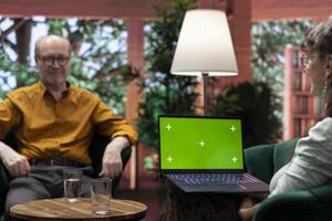 Elderly couple in comfortable home enjoying a conversation next to mockup display, emphasizing senior living and companionship. Happy joyful husband and wife having fun laughing. photo