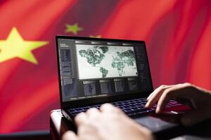 Chinese PSyOp operator using laptop device, making bot accounts attacking Western powers. Close up of IT professional working for China coding troll farm promoting communism doctrine on social media photo