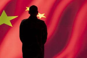 Chinese military soldier standing proud in front of flag, feeling pride in serving country. Communist red army officer in command control room standing isolated over China flag background photo