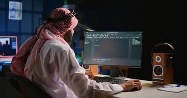 Trained muslim engineer writing code on computer screen while in office using Java programming languages. Middle Eastern developer working on fixing database errors while working from personal office photo