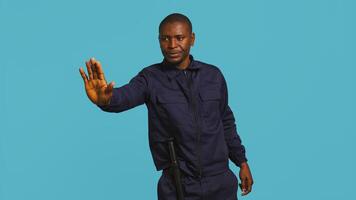 Portrait of security guard doing stop sign gesturing to intruder while overseeing premises. Private law enforcement worker showing halt hand gesture to trespasser, studio backdrop, camera B photo