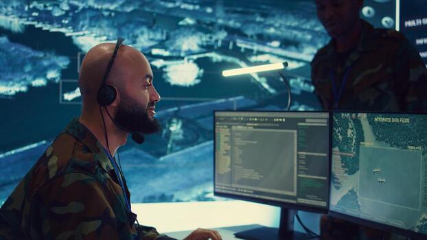 Male IT specialist operating on reconnaissance system to transmit real time data for new field mission, working in military command center. Telecommunications operator provides air support. Camera B. photo