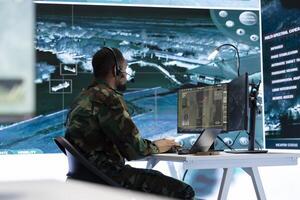 Military personnel in a modern command center work on data processing, integrating real time surveillance footage from satellite systems. Working with big screen and computer intelligence. photo