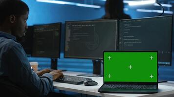 Isolated screen laptop next to programmer coding in server farm, ensuring valuable data remains shielded from threats. Worker safeguarding hardware against unauthorized access with chroma key notebook photo