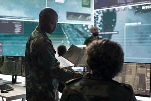 Intelligence analyst collecting satellite surveillance real time data and transmitting battlefield information to infantry unit. Trooper engineer working on military defense program, army division. photo