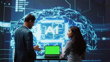 AI developers using isolated screen device for business data analysis. IT department staff members work on chroma key notebook to automatize tasks using artificial intelligence, camera B photo