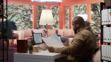Business owner conducting strategic research on office spaces and building layouts, using blueprints and sketches to draft and organize a new creative workspace. Office hunt relocation. Camera B. photo